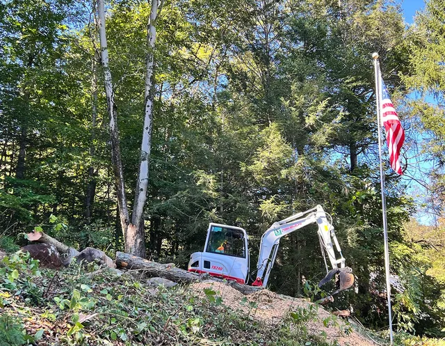 An excavator is sitting on top of a hill next to a flag