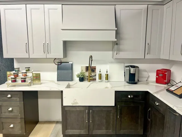 Kitchen with white and brown cabinets, farmhouse sink, gold faucet, and appliances.
