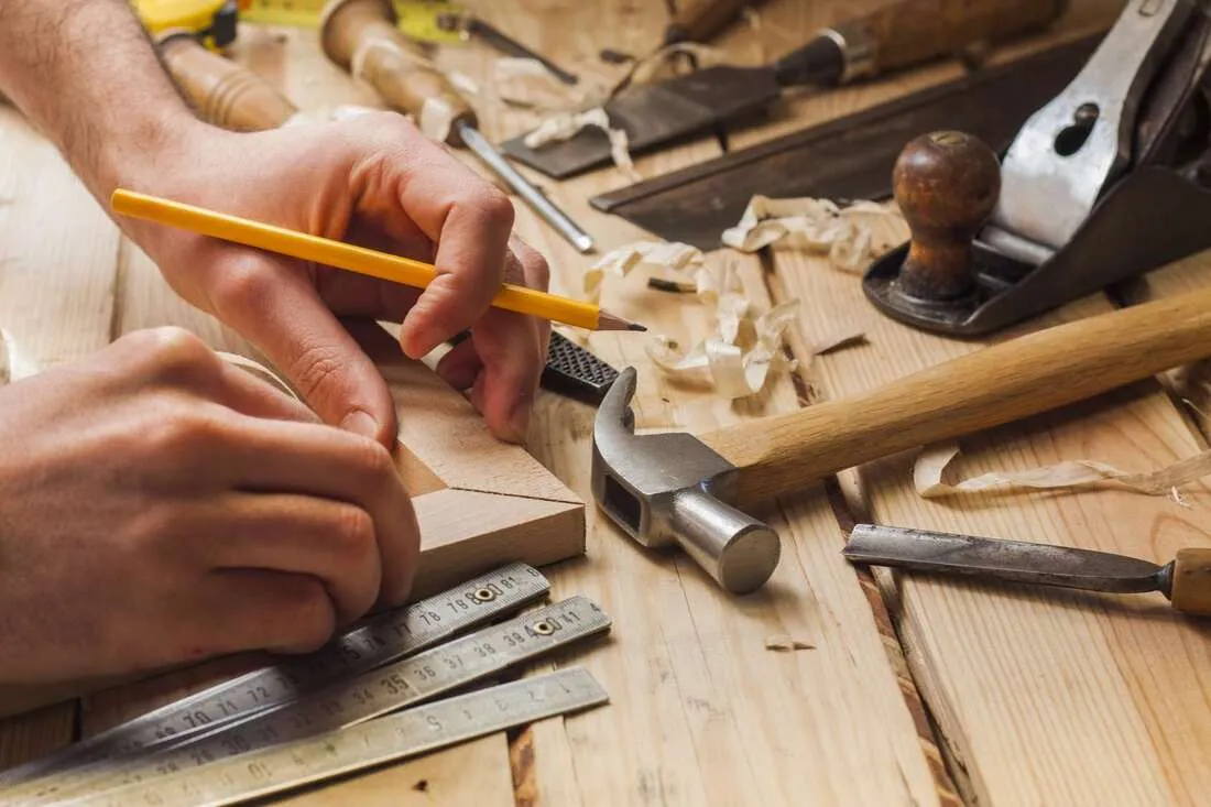 Carpentry Image - man putting pieces of wood together with tools around