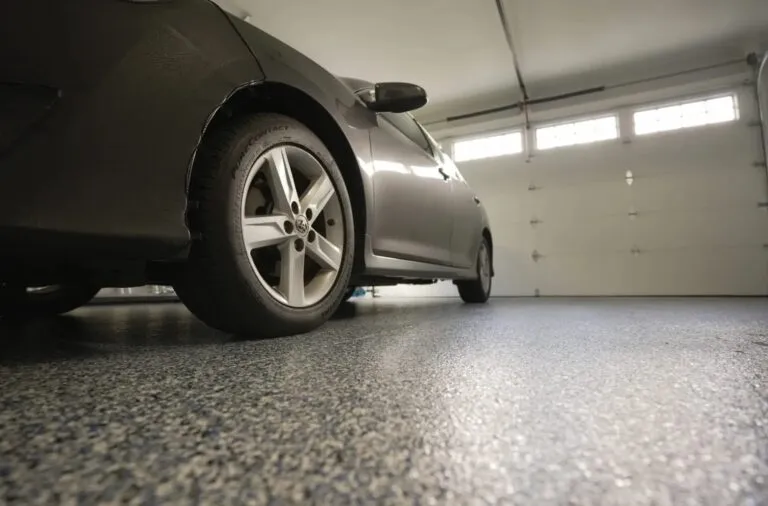 An garage car port with door closed and car inside, with newly sealed epoxy floor recently installed.