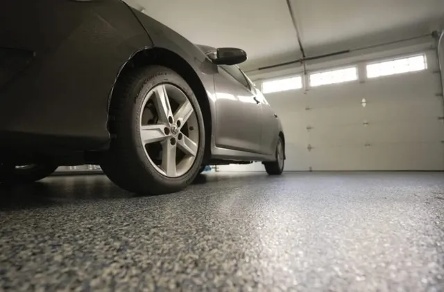 An garage car port with door closed and car inside, with newly sealed epoxy floor recently installed.
