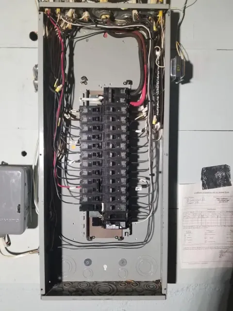 Open electrical breaker panel with exposed wiring and multiple circuit breakers in a wall-mounted box