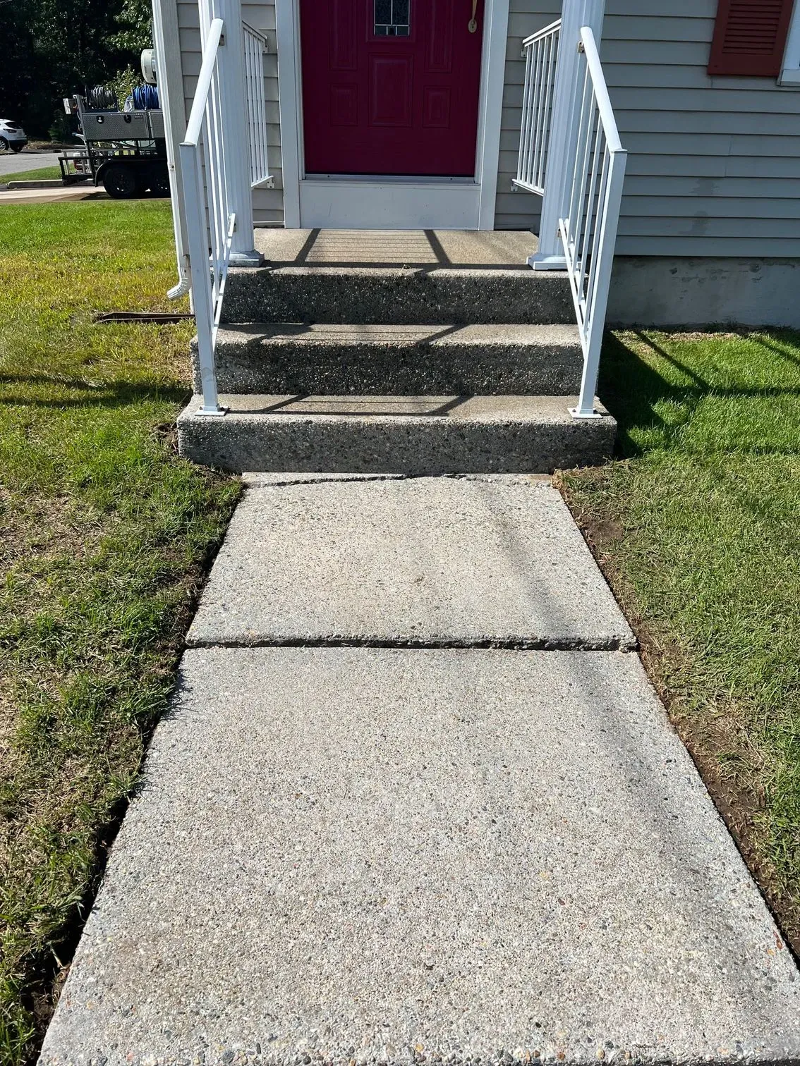 A concrete walkway leading to the front door of a house.