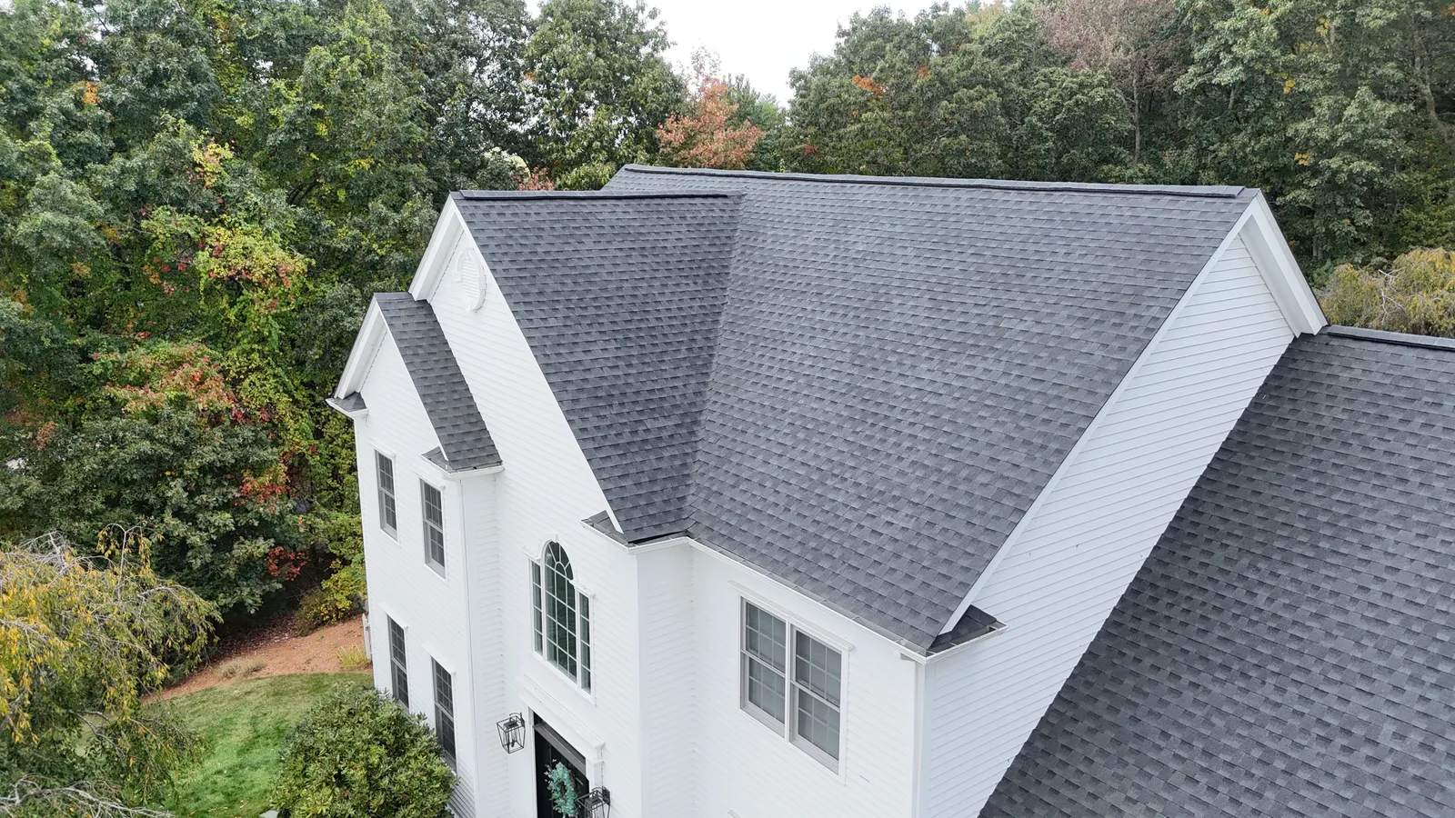 Aerial view of a white home with a newly installed gray shingle roof