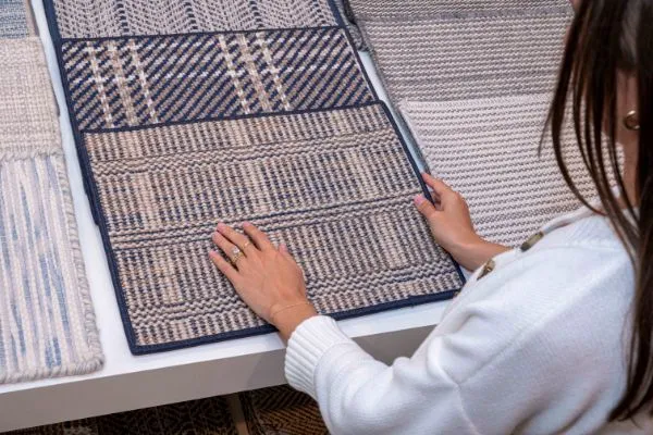 Woman selecting a textured blue and beige carpet sample. This image can be used for carpet and floor installation blog content.