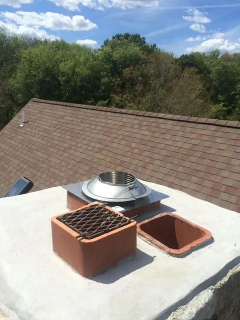 A chimney on top of a roof with trees in the background.
