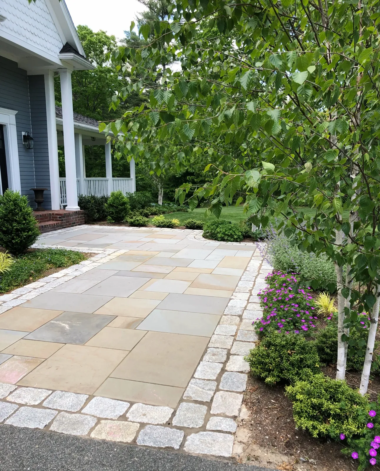 Blue stone pavers with a granite cobble border make for a beautiful garden entry at this Boxford home.