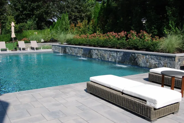 A spa-like setting was created at this Andover landscape project with an addition of a gunite pool with sheer descent fountains and surrounding gardens and patios for lounge chairs, umbrellas and outdoor entertainment.