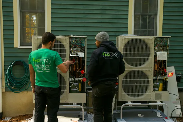 Two MJ Pro Energy technicians wiring Mitsubishi heat pump outdoor units