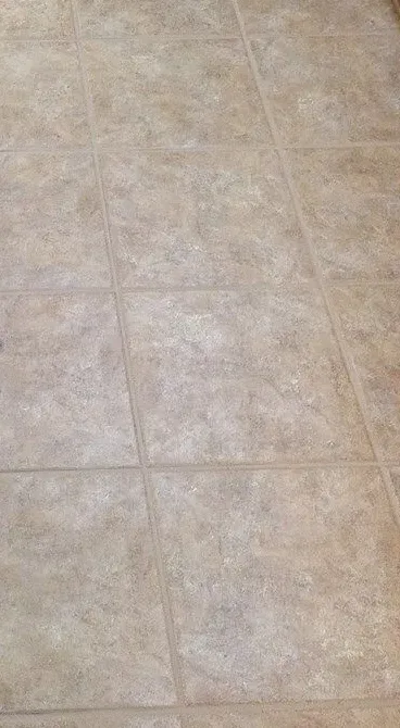 Accessible beige tiled shower with bench, grab bar, multiple shower heads and fixtures.
