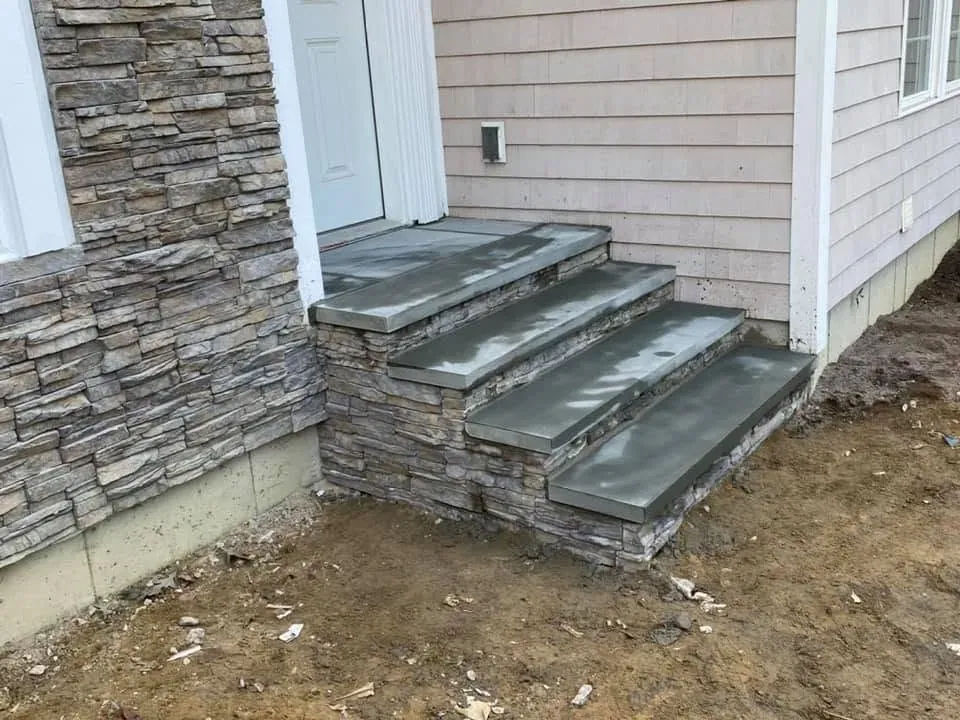 Bluestone entry steps installed beside a stone veneer wall