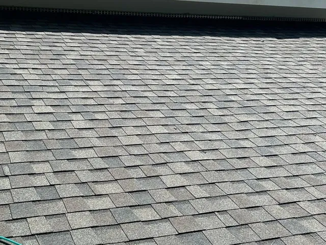 Gray shingled roof with a dark ridge line under a bright sky