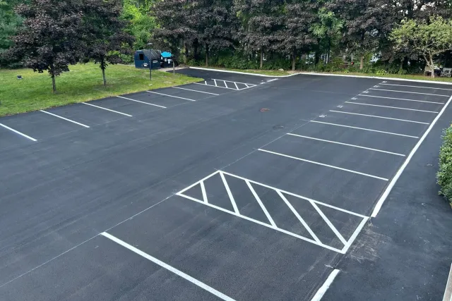 Newly paved asphalt parking lot with white painted parking space lines.