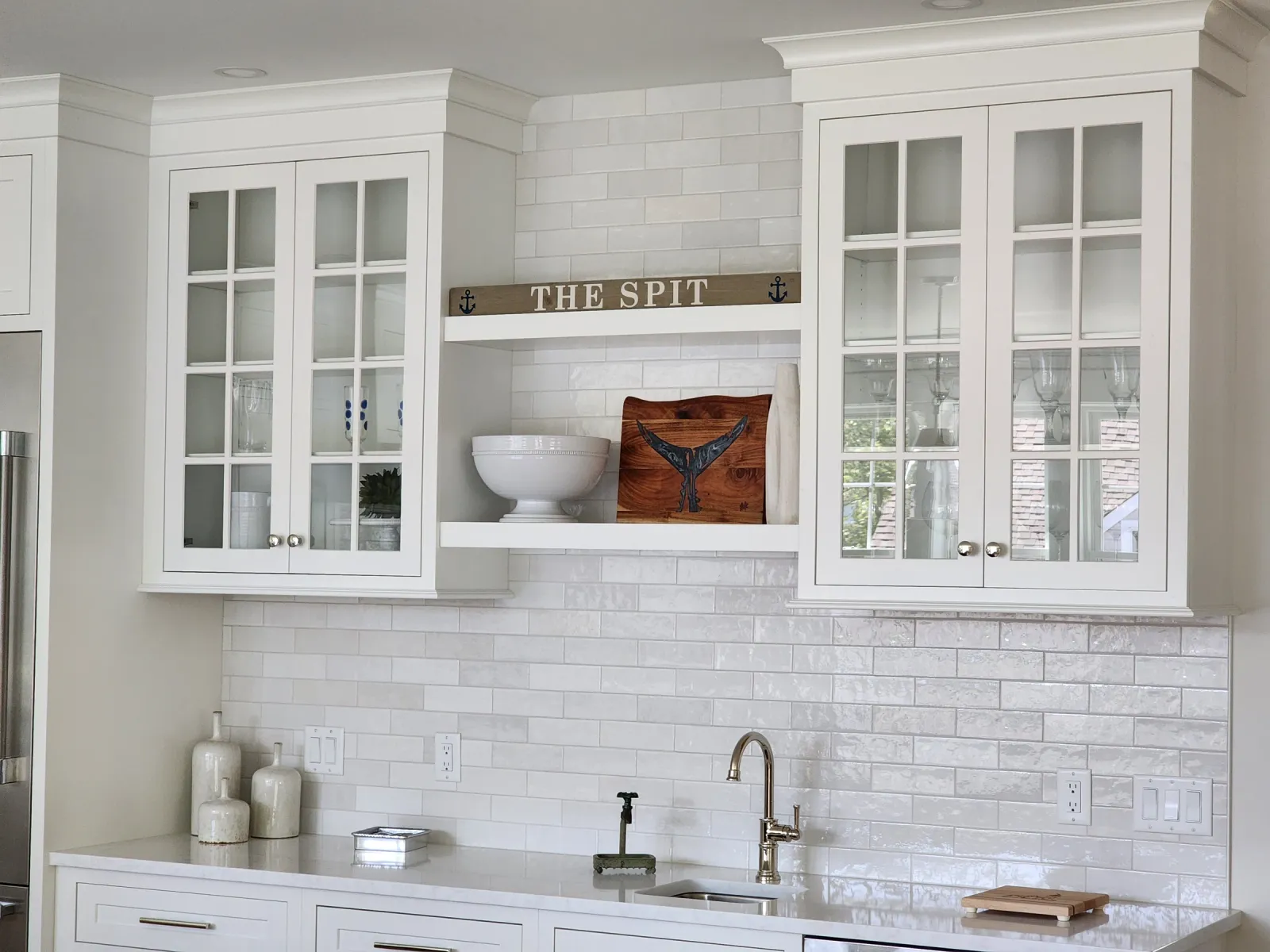 White kitchen backsplash beneath glass-front cabinets and an open shelf
