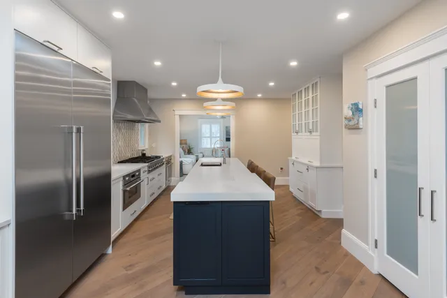Hingham kitchen with navy island, white Mouser cabinetry, and herringbone glass mosaic backsplash