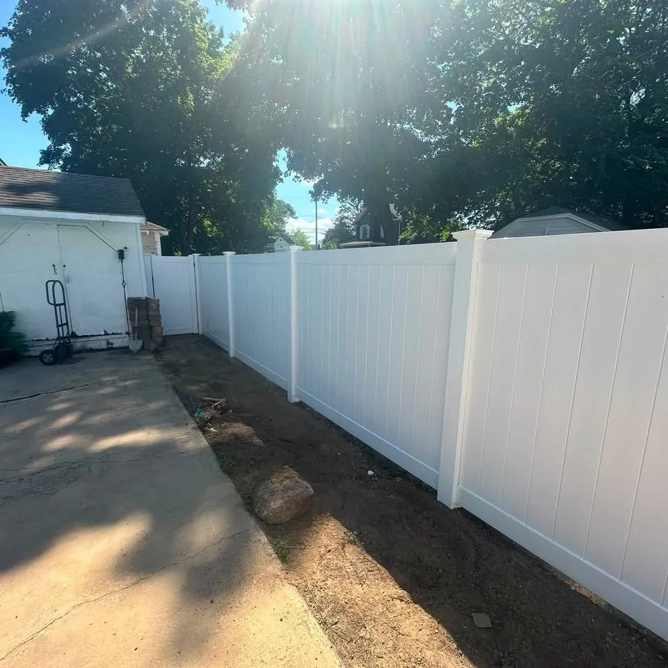 New white vinyl privacy fence alongside a driveway