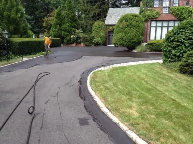 A man is walking down a curved driveway in front of a house.