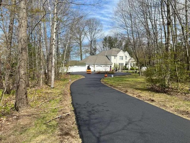 Asphalt driveway with a large house in the background