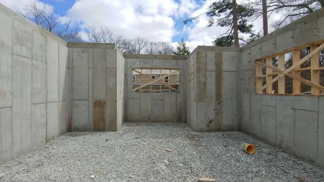 A basement under construction with concrete walls and wooden beams.