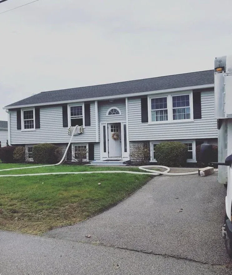 Front view of house getting blown-in cellulose insulation services by NetZero Insulation Technologies crew.