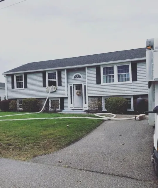 Front view of house getting blown-in cellulose insulation services by NetZero Insulation Technologies crew.