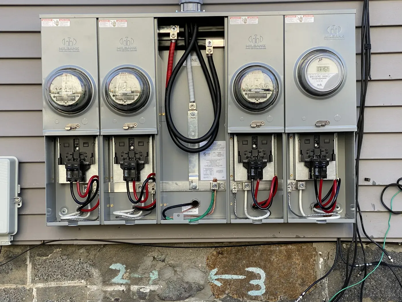 Bank of electrical meters and service disconnects installed on the exterior of a multi-unit building