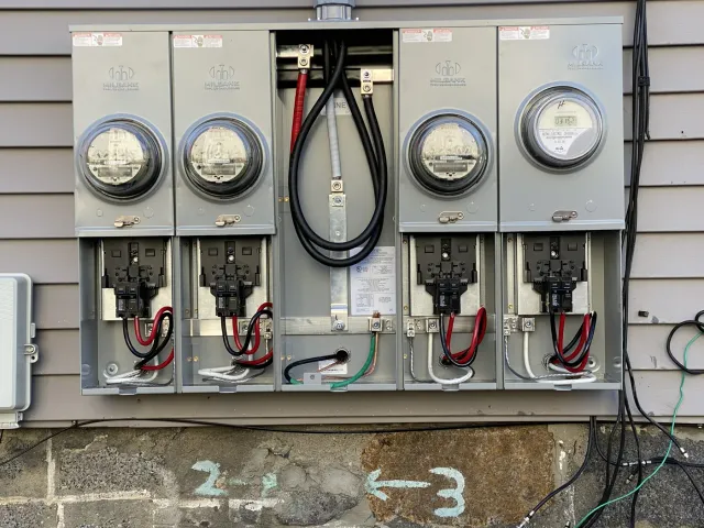 Bank of electrical meters and service disconnects installed on the exterior of a multi-unit building
