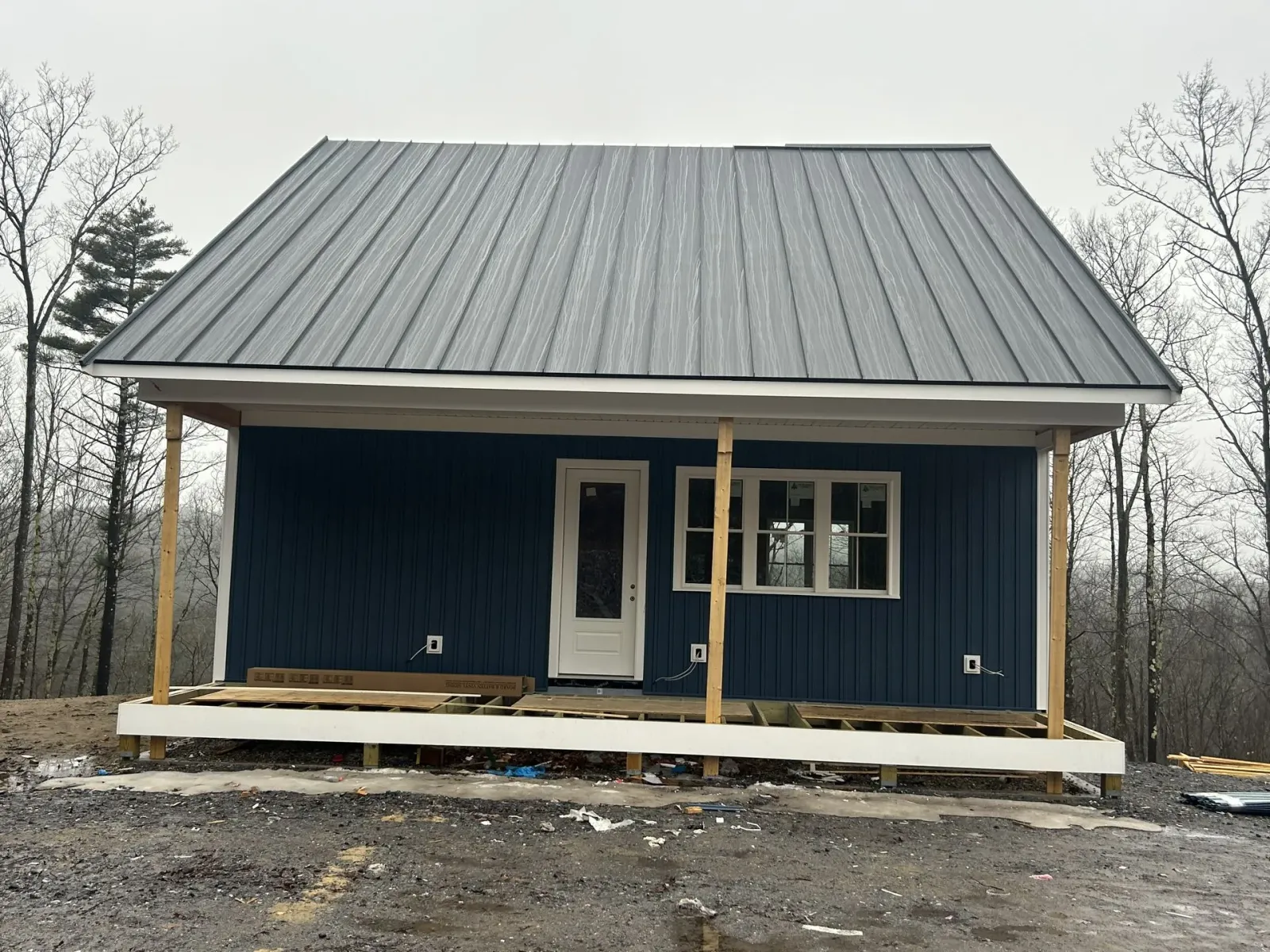 A blue house with a metal roof and a porch