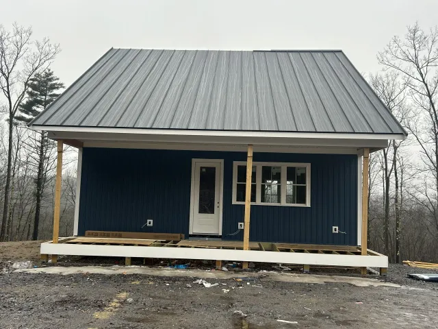 A blue house with a metal roof and a porch