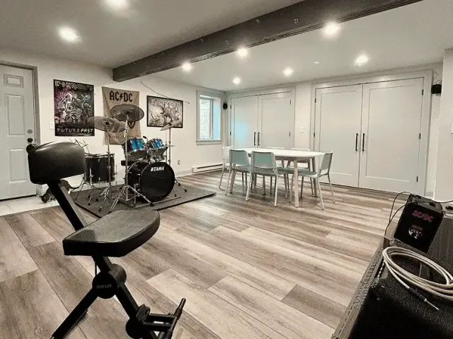 Finished basement with music area, drum set, and workout equipment in a modern home.