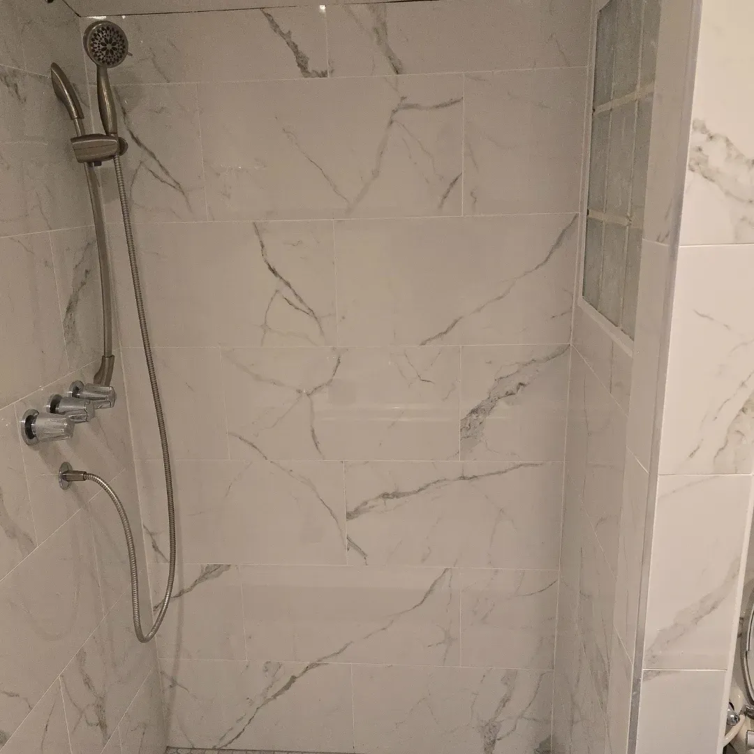 White Carrara marble shower walls with handheld fixture by Link Services Pro in Worcester, MA