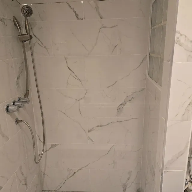 White Carrara marble shower walls with handheld fixture by Link Services Pro in Worcester, MA