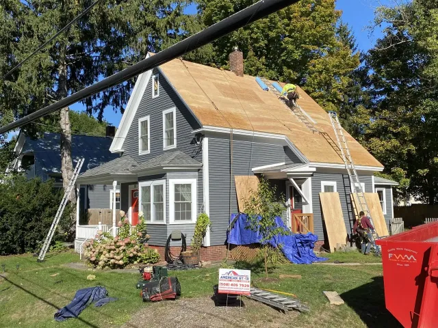 House with roof repair in progress, tools and materials scattered across the front yard.