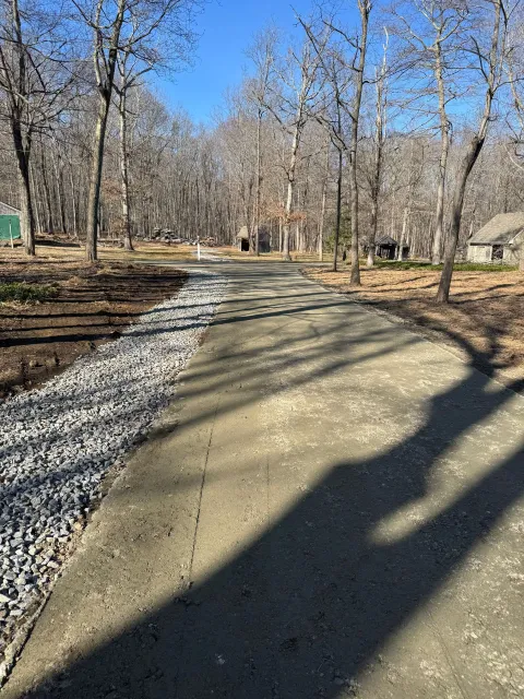 Wooded park trail curving ahead, bordered by gravel and long tree shadows on a sunny day