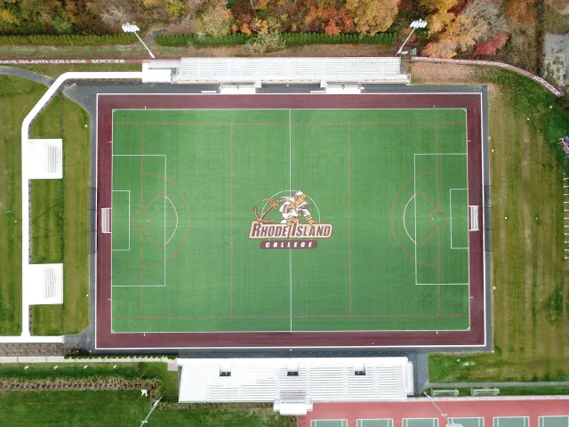 Aerial view of a soccer field at Rhode Island College with a logo in the center featuring a knight mascot and the Rhode Island College name.