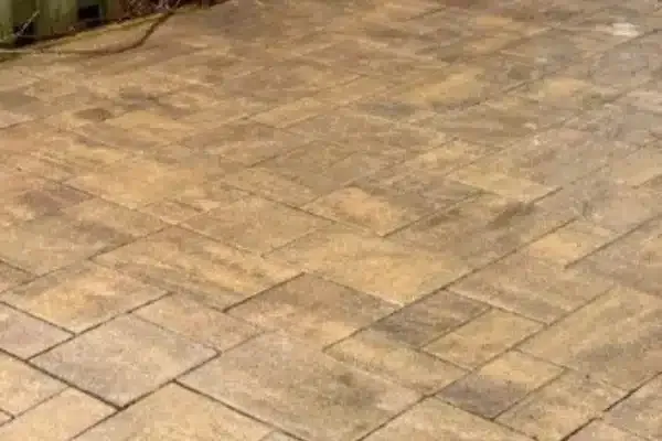 After: Paved patio with rectangular stones arranged in a pattern, slightly wet, showing a textured surface.