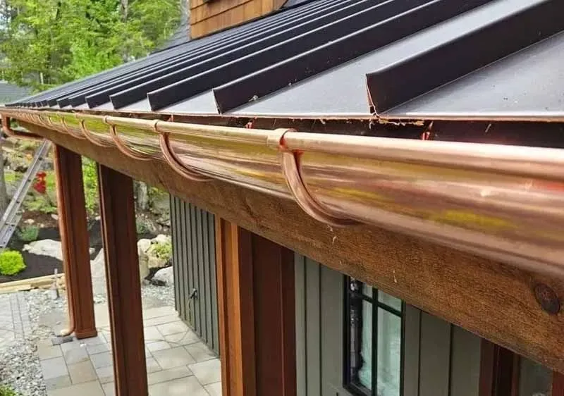 A close up of a copper gutter on the side of a house.