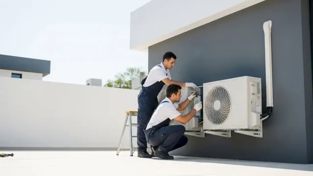 A licensed installer performing an air conditioner installation in a Massachusetts home.