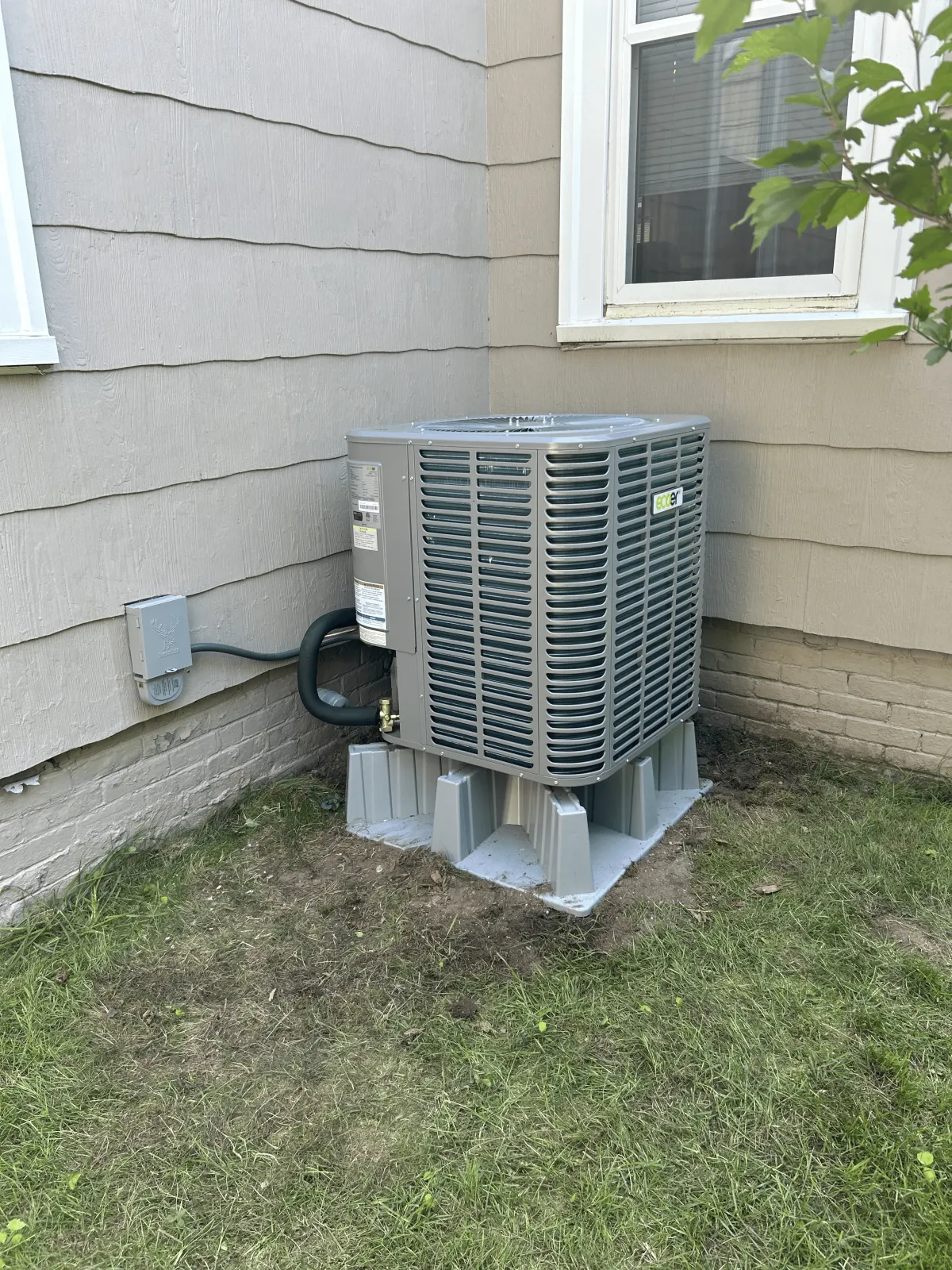 New AC condenser unit installed on concrete pad beside residential home in Rockland