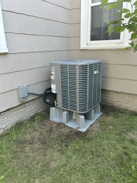 New AC condenser unit installed on concrete pad beside residential home in Rockland