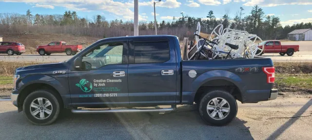 Blue pickup truck loaded with scrap metal, parked outdoors in a lot