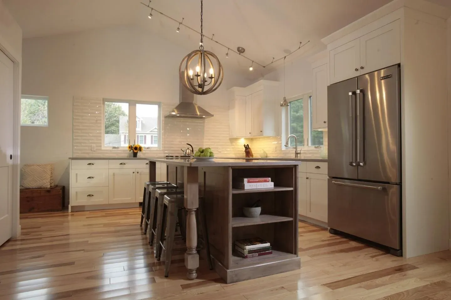 Circular pendant lighting above kitchen island with built ins by Oxland Builders in New Hampshire