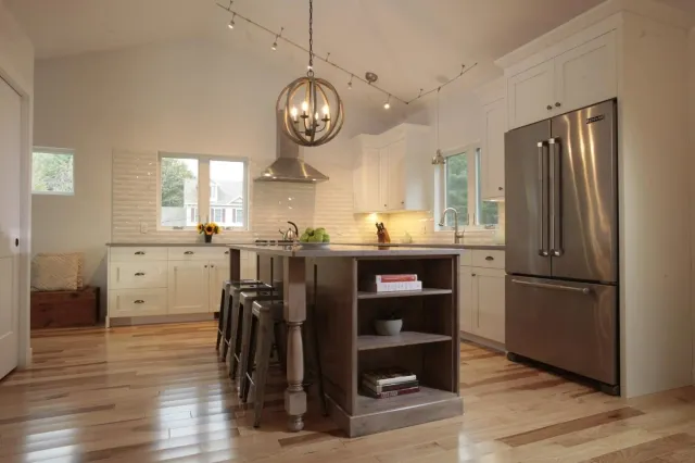Circular pendant lighting above kitchen island with built ins by Oxland Builders in New Hampshire