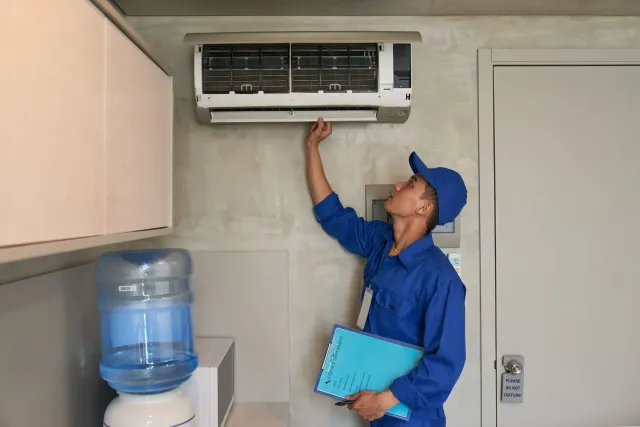 HVAC technician servicing a wall-mounted air conditioning unit