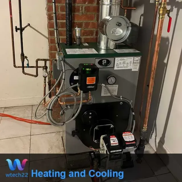 A gray heating boiler with connected copper pipes and chimney in a basement setting.