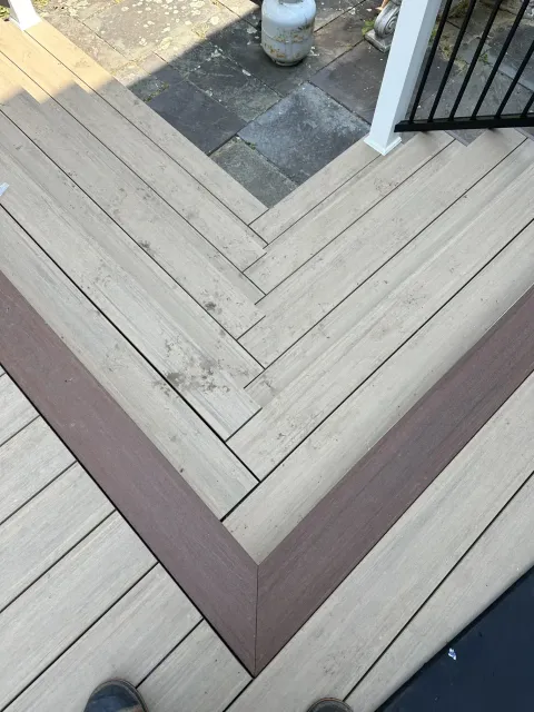 composite-deck-corner-with-chevron-pattern-and-contrasting-border-boards-and-black-aluminum-railing-in-oxford-connecticut.webp