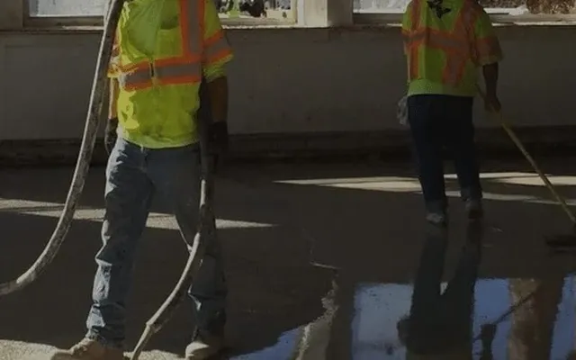 Two construction workers smoothing wet concrete