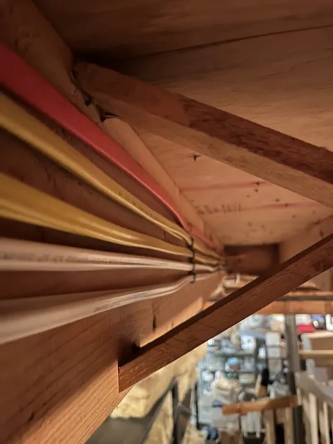 Perfectly organized wires stapled to a beam in a new wiring project for a home