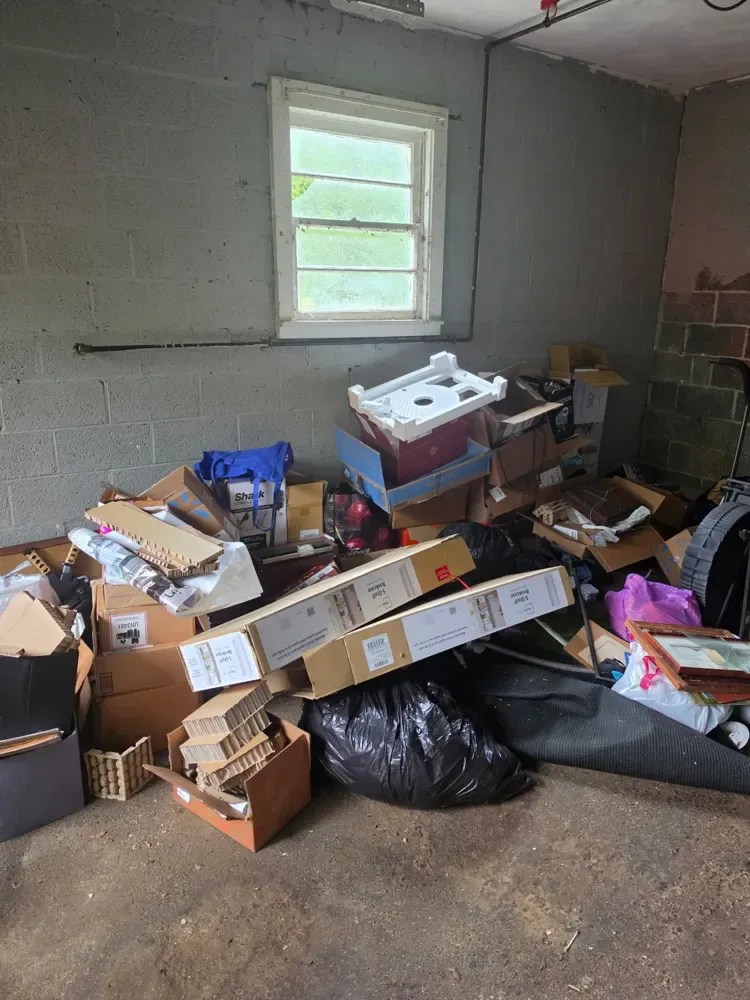 A cinder-block storage room piled with boxes and bags before the cleanout