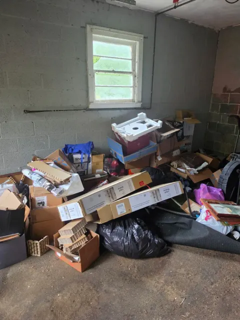 A cinder-block storage room piled with boxes and bags before the cleanout